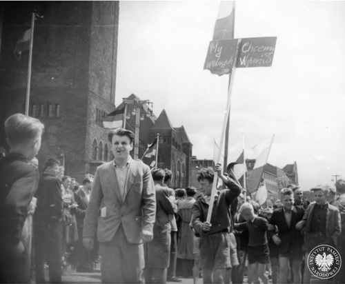 Demonstranci z transparentem „My chcemy wolnych wyborów”, na tle Zamku Cesarskiego w Poznaniu, ówczesnej siedziby Prezydium Miejskiej Rady Narodowej, czerwiec 1956 r. Fot. AIPN