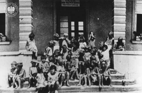 Grupa dzieci ocalałych z obozu koncentracyjnego na schodach domu opieki, 1945 rok