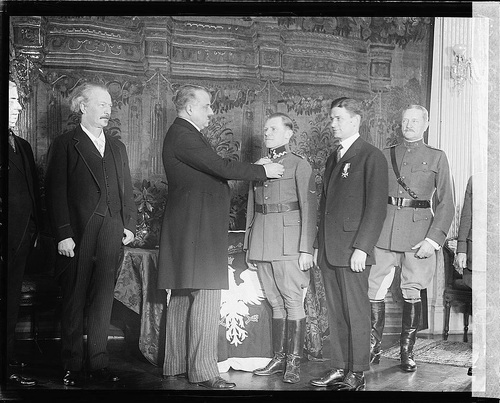 Uroczystość przypięcia orderu Virtuti Militari dwóm lotnikom amerykańskim kpt. Harmon’owi Rorison i por. Kenneth’owi Shewsbury w siedzibie polskiego poselstwa. Order przypina Kazimierz Lubomirski, po lewej stronie stoi premier Ignacy Jan Paderewski, a od prawej strony stoi gen. John Pershing. 1921 r. (fot. z zasobu Biblioteki Kongresu, domena publiczna)