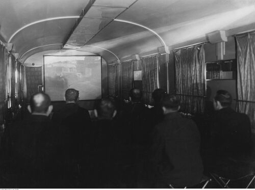 Wnętrze wagonu kinowego podczas projekcji. Widoczni pasażerowie oglądający film, 1936 r. (NAC)